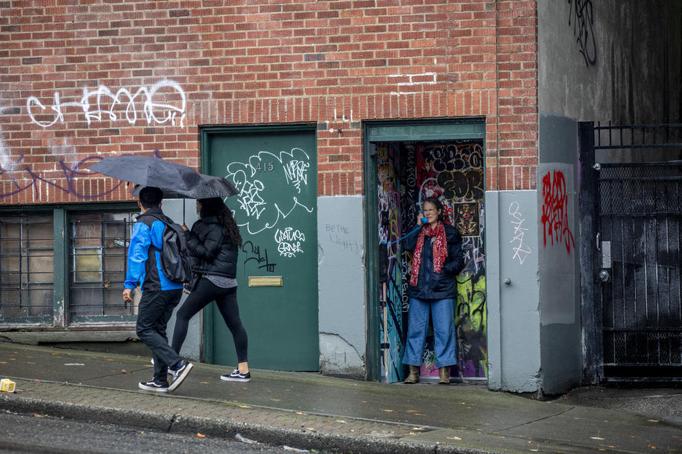 Person stands in makeshift photo booth while two people walk by