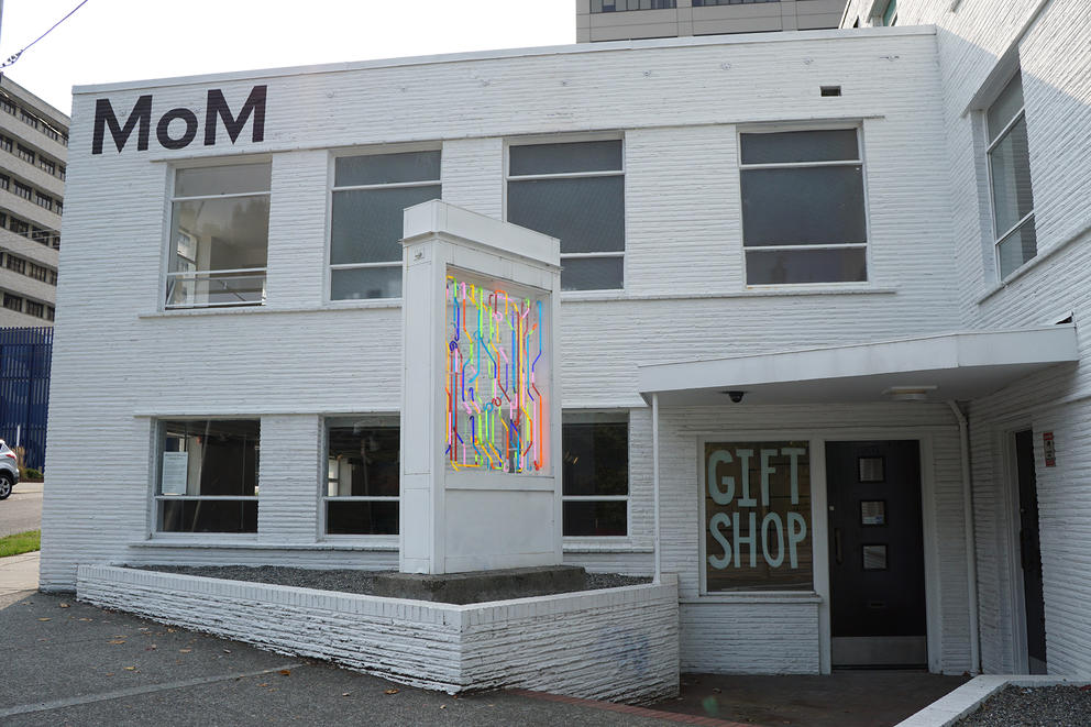 Midcentury building painted white with neon artwork in front