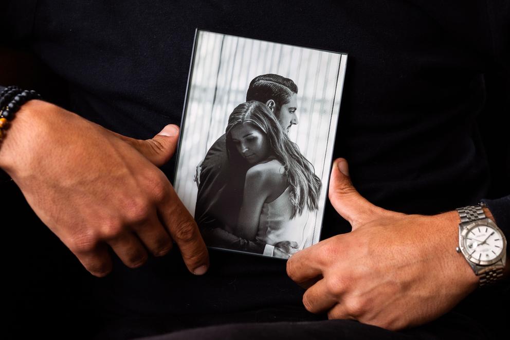Abraham Dairi's hands holding a photo of him and his wife, Holly, embracing