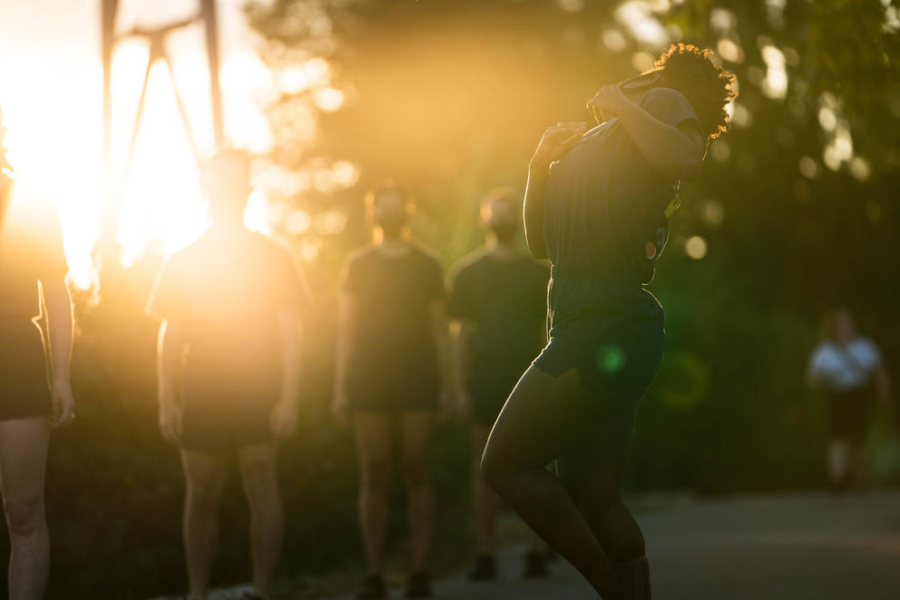 Person dances as the setting sun illuminates the photo from the left upper corner