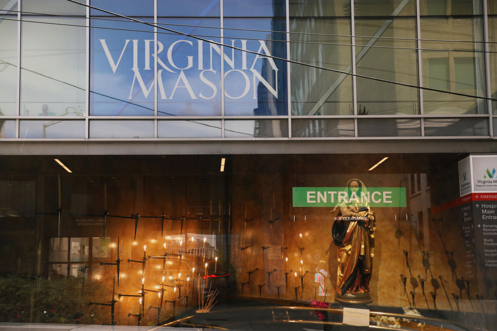 Double exposure photograph showing Virginia Mason signage over a statue of the Virgin Mary inside a church
