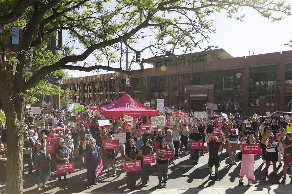 A crowd of pro-choice protesters hold signs reading "I stand with Planned Parenthood" and "Together we fight for all"