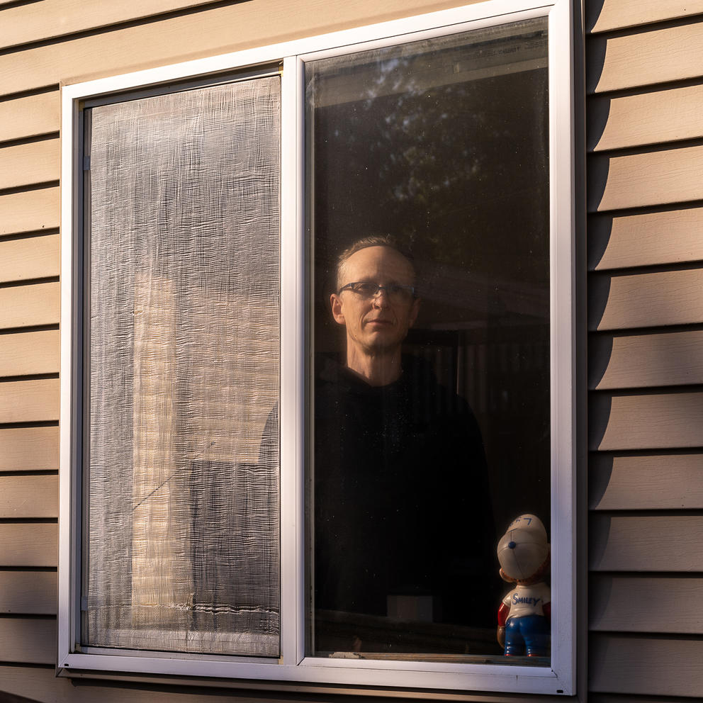 Person standing behind a window in soft evening light