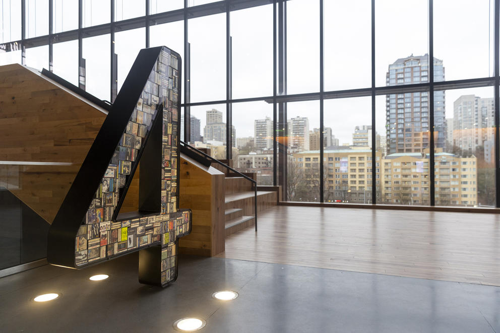 Giant number 4 filled with casettes seen in empty room with large glass walls