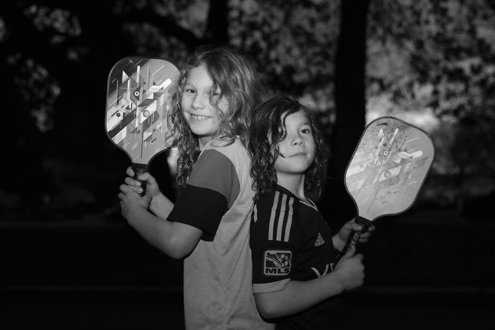 A close up of two young boys back to back holding up paddles
