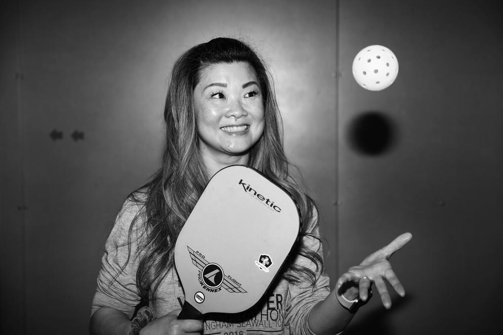 A close up of a woman holding a paddle and tossing a ball in the air