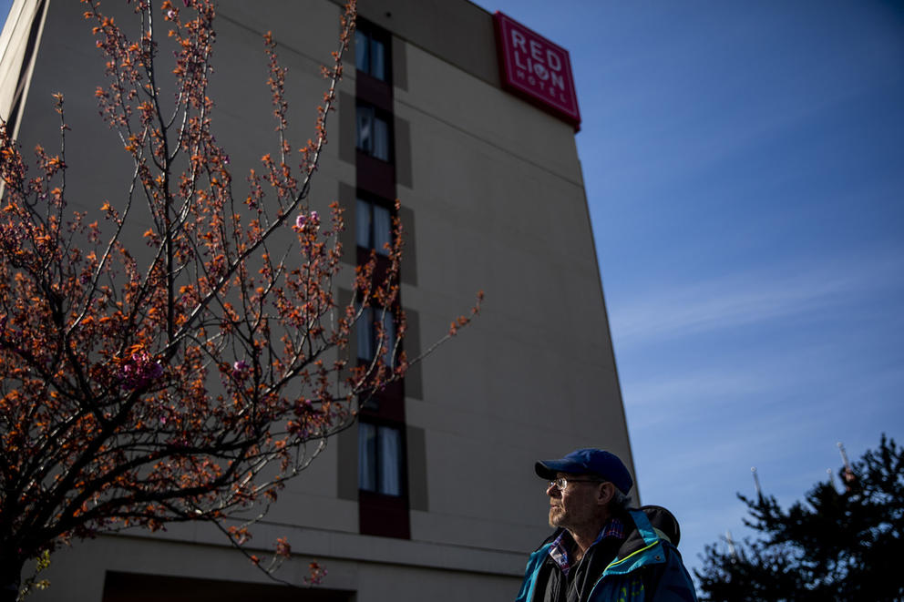A man sits in front of a Red Lion hotel