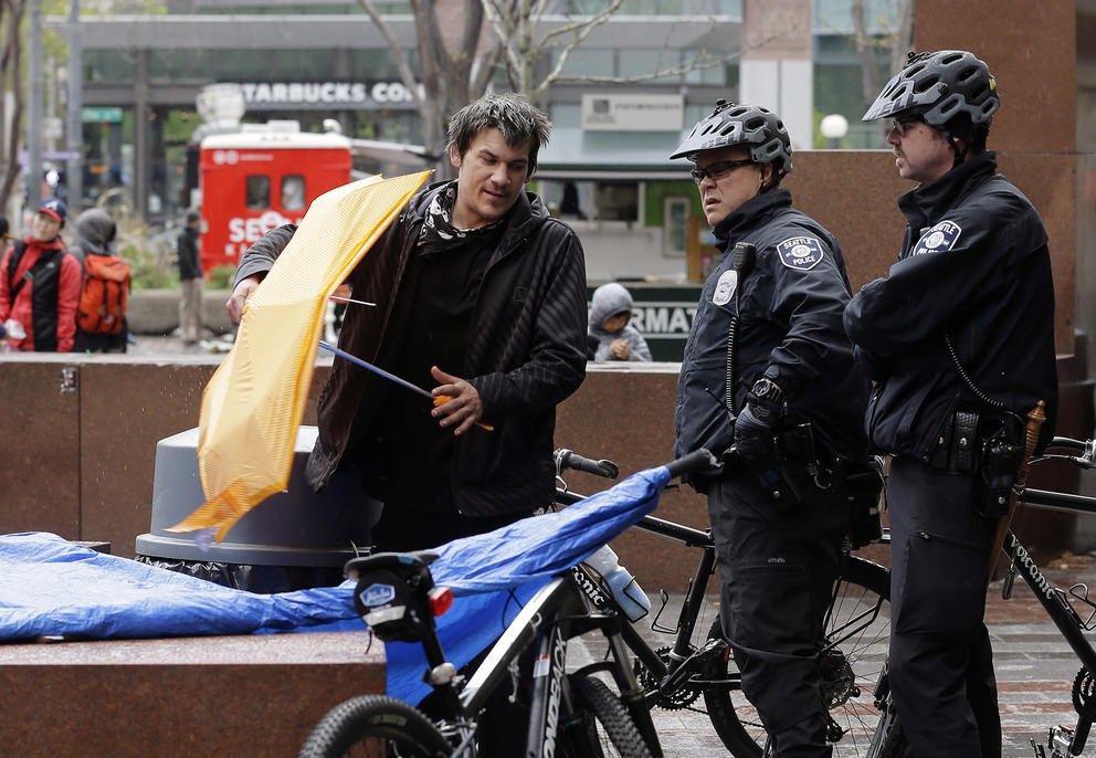 Police officers speak to an unhoused man
