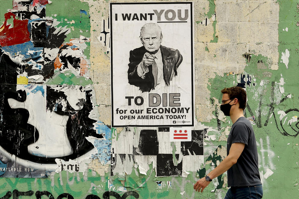 man walking past trump poster
