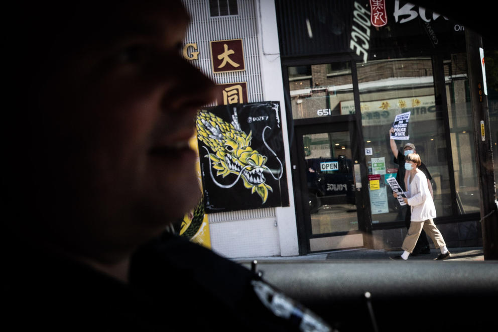 police officer in patrol vehicle, protesters outside window