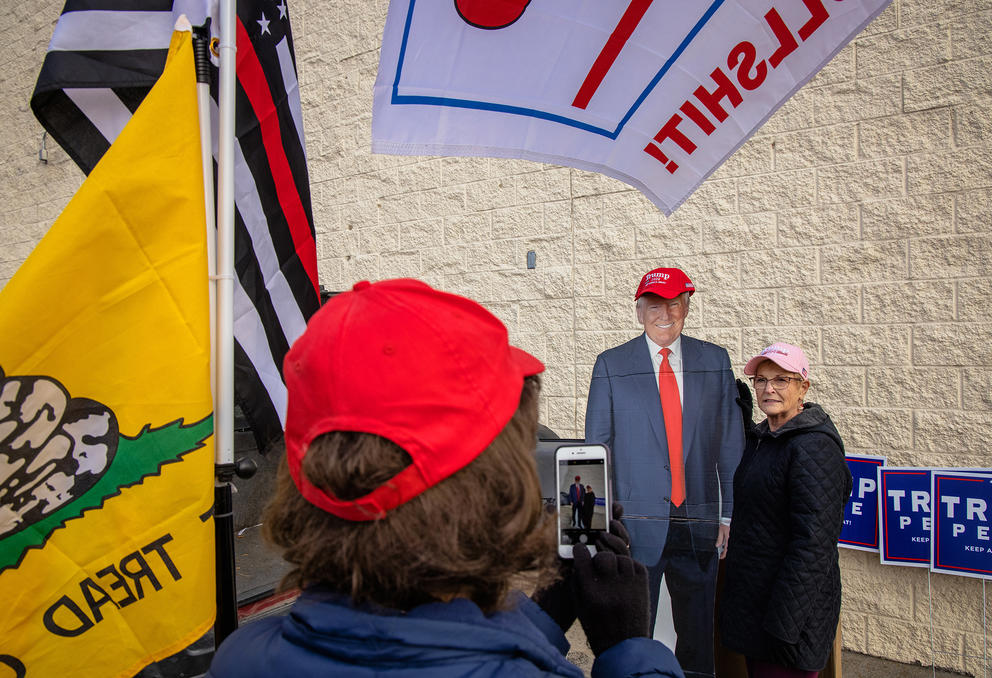 A woman poses with a cardboard cutout of Trump