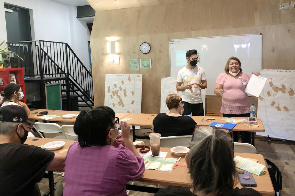A group of people in a room with white boards discussing maps. 