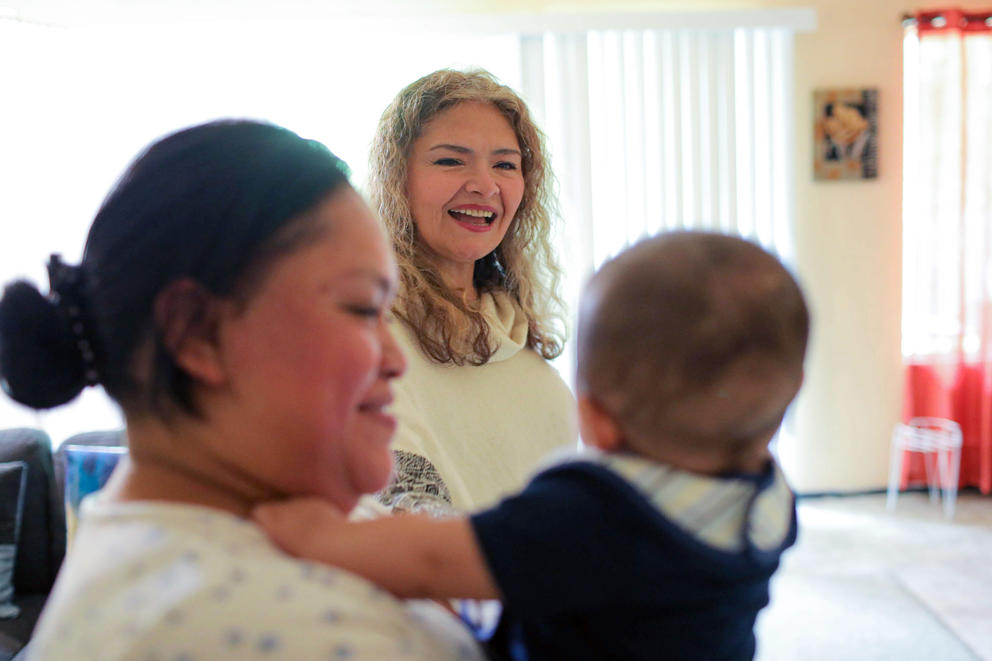 Margarita Celis, center, visits with one of her clients, Victoria Ramirez, and Ramirez's 5-month-old Henry.