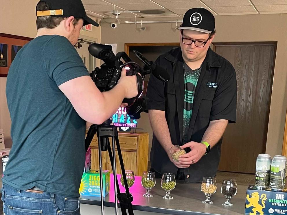 A person holding a camera to a man holding a glass