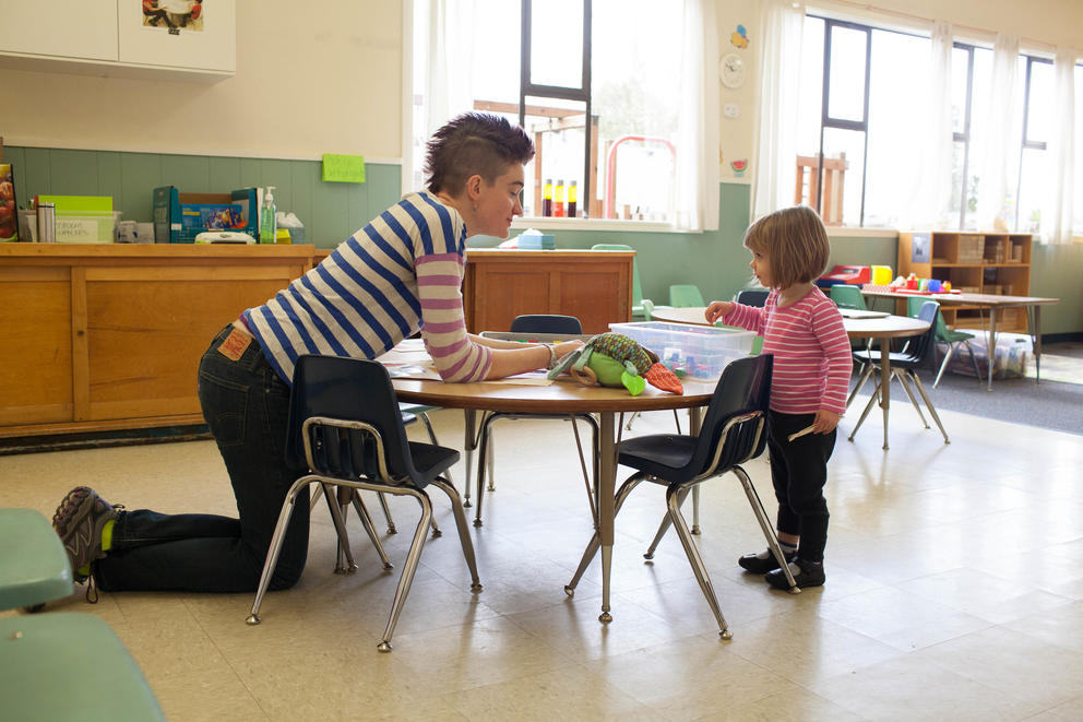 Teacher kneeling at table with child