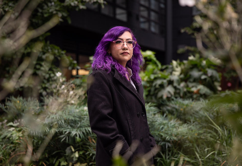 Stephanie Valerdi poses in front of lush greenery. 