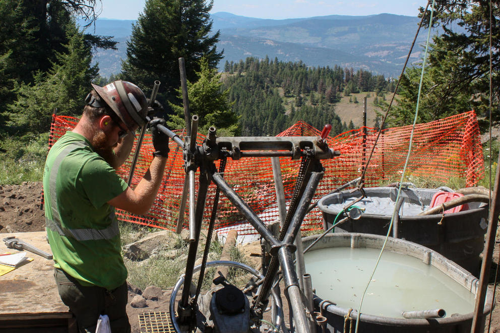 A man uses some machinery on a hilltop