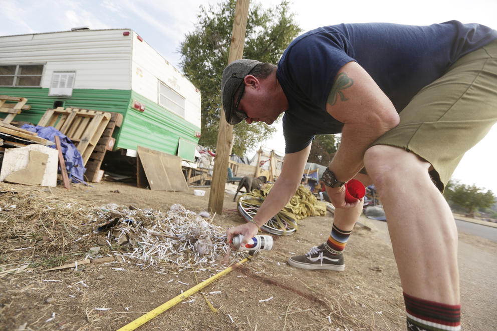 Washington State Department of transportation worker marks line for fence around Camp Hope encampment 