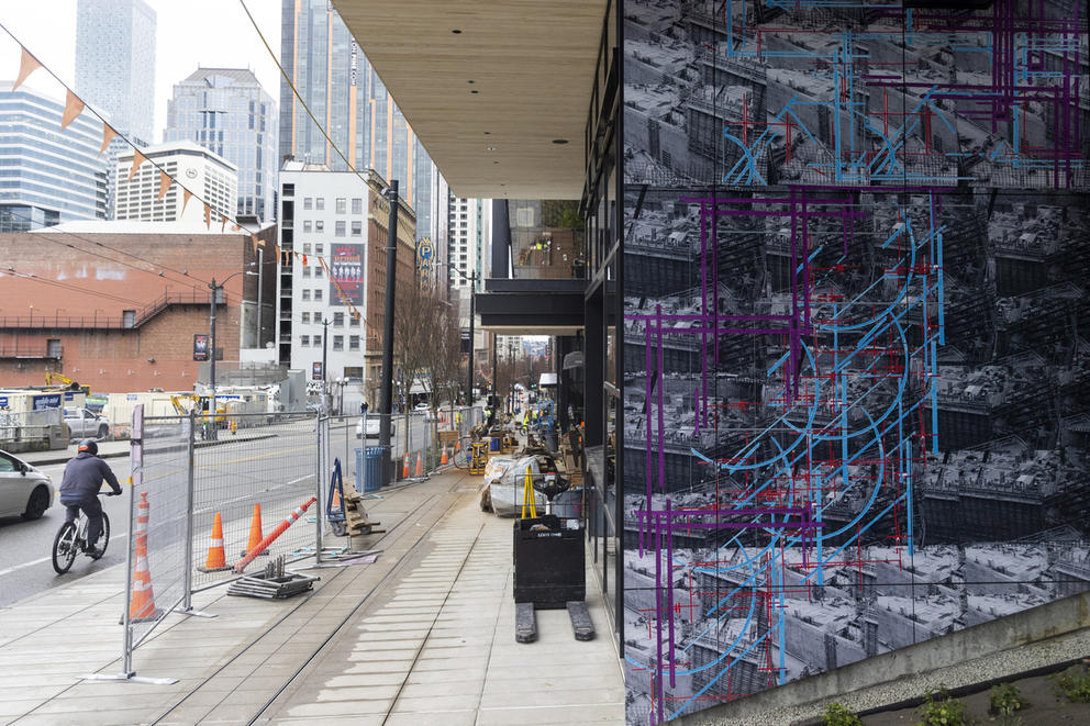 A wall featuring purple and blue stripes on black and white on the right, construction workers to its left