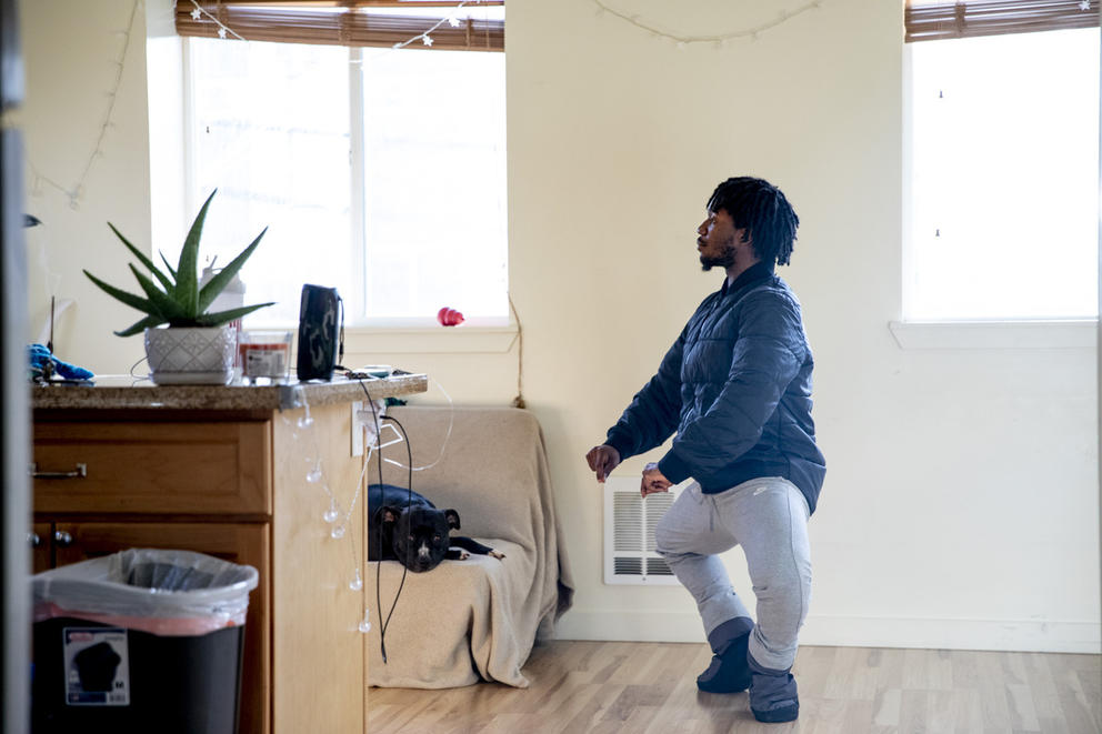 Person in their living room, framed by two windows, in ballet position