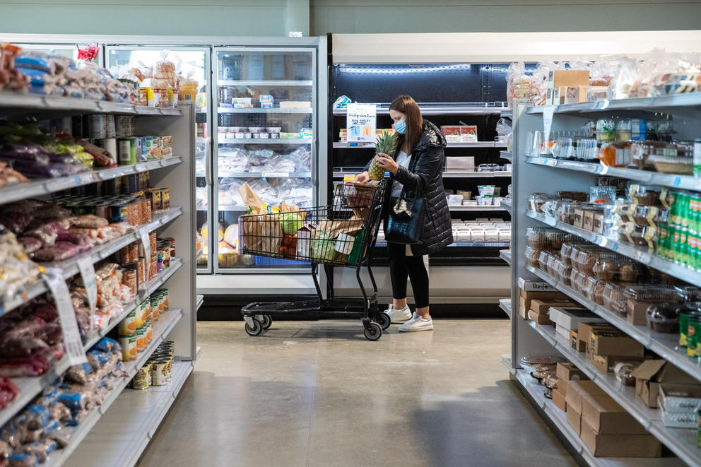 a woman pushes a grocery cart through the aisles of the ballard food bank