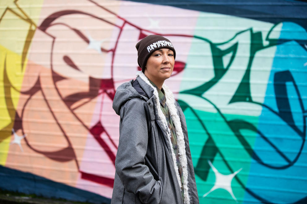 A portrait of a woman standing in front of a colorful mural