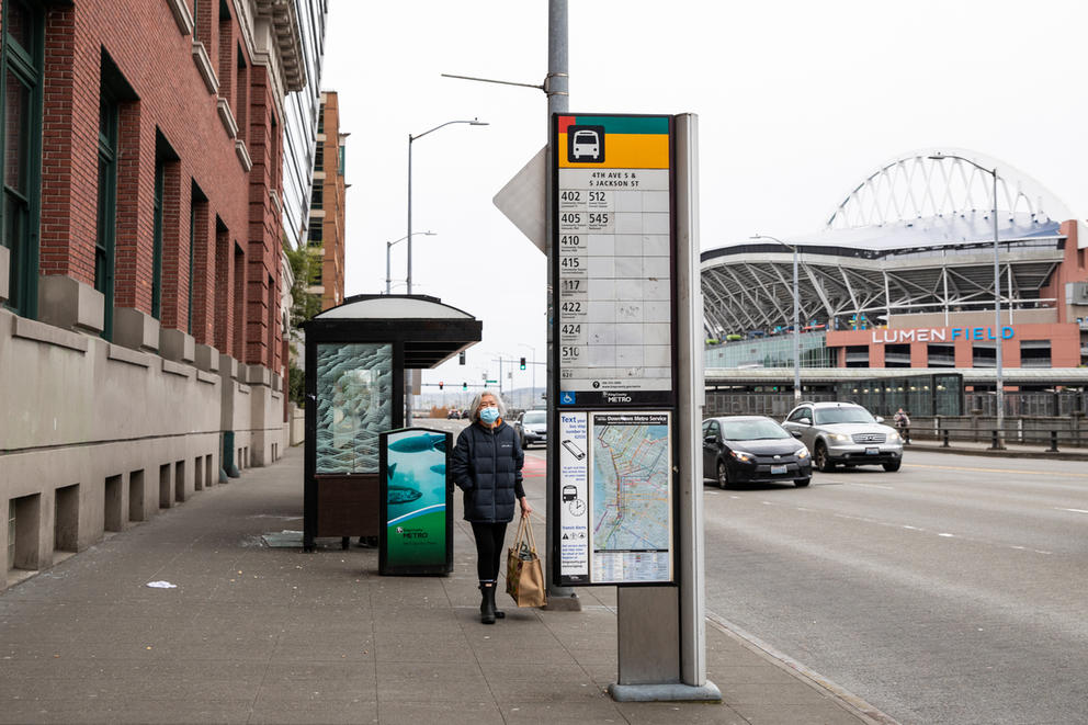A woman waits at a bus stop on 4th ave in chinatown-international district