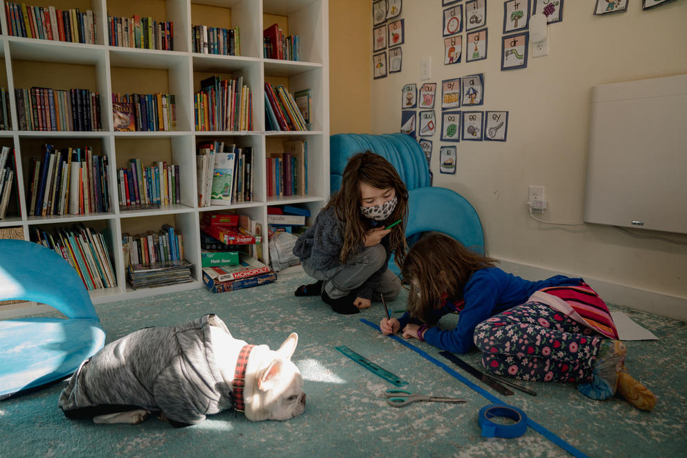Students sit on the floor with a dog.