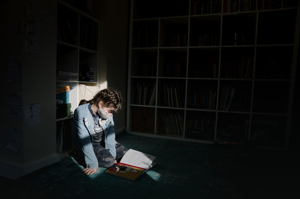 A young student sits on a floor and reads.