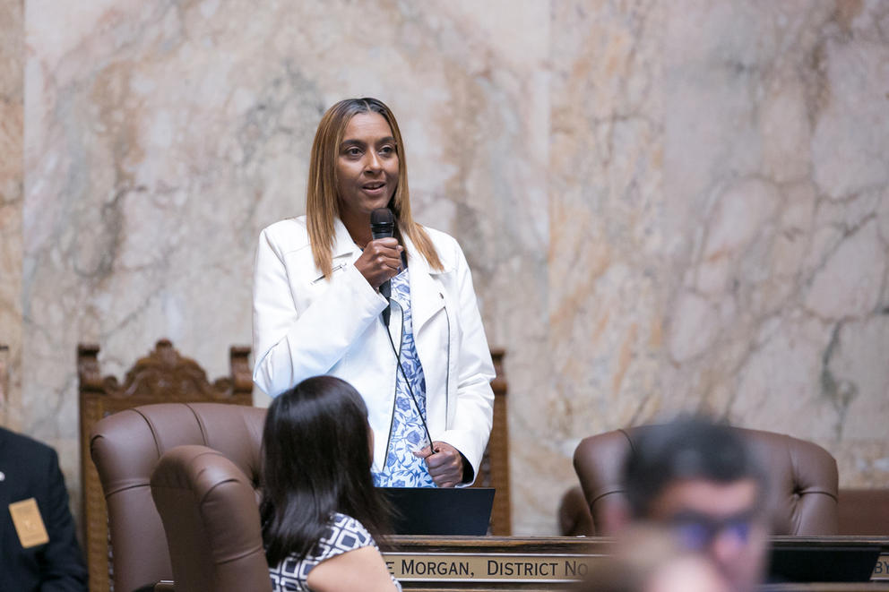 Rep. Melanie Morgan stands with a microphone, speaking 