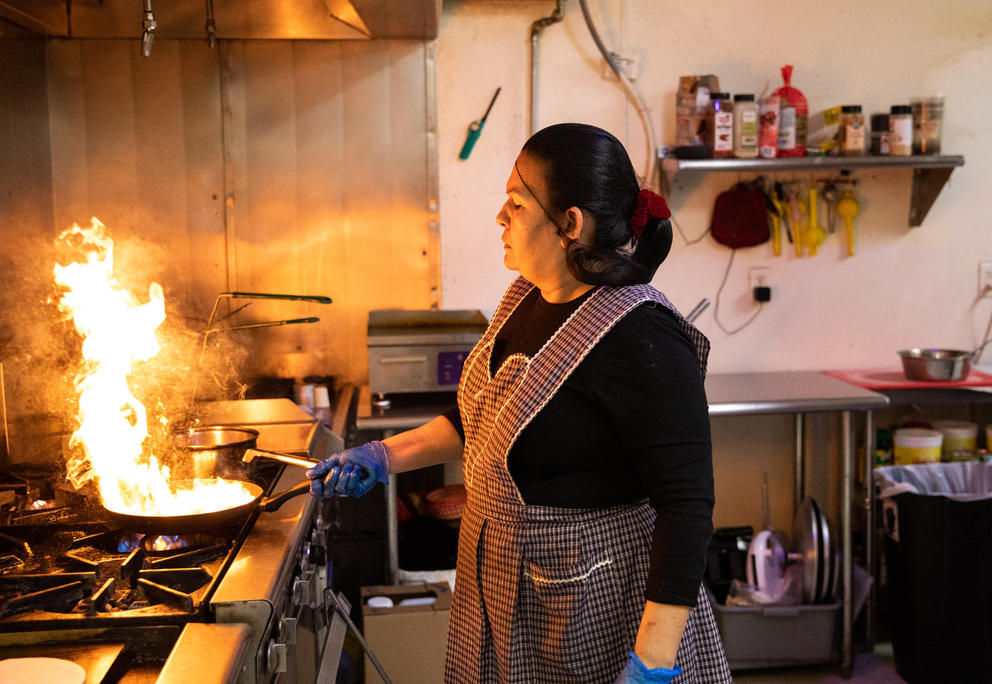 Sanchez cooks food in a flaming pan