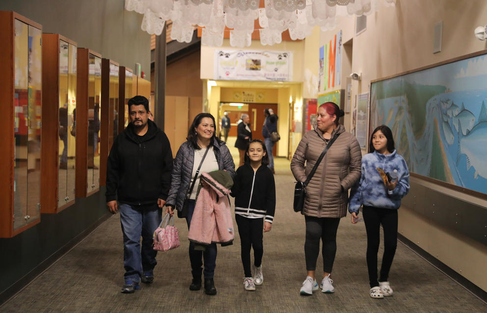 Two families walk toward the view in a school hallway.