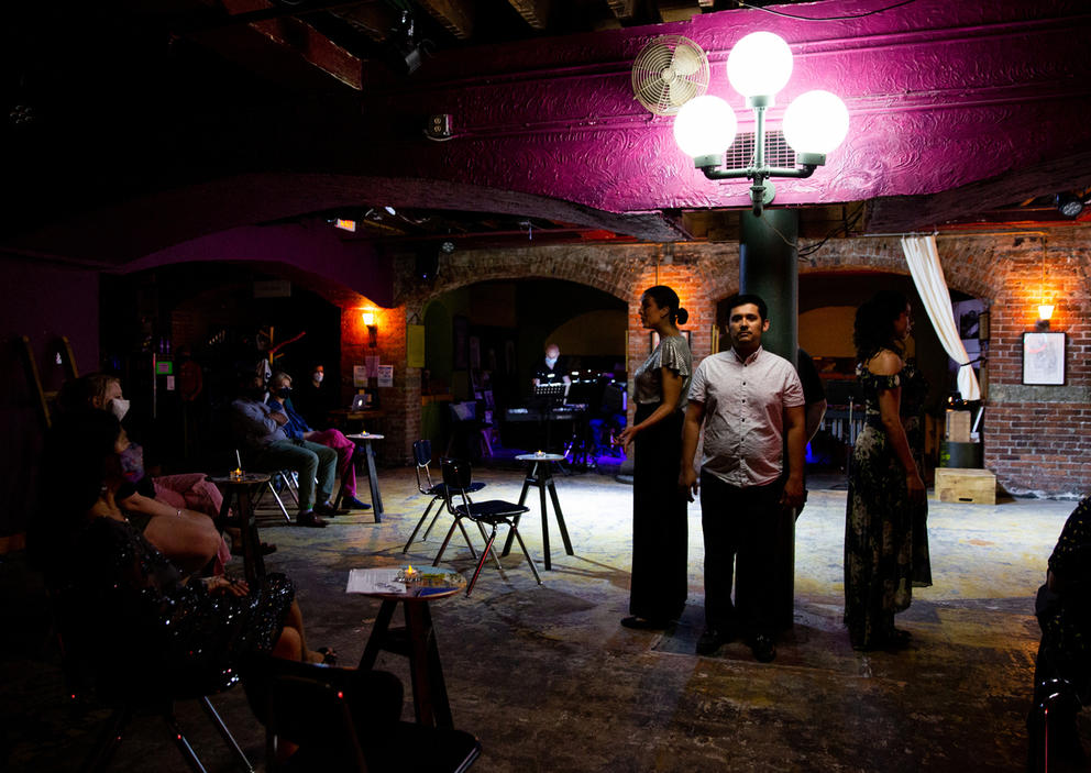 Three actors rehearse lines while standing in a semi-circle