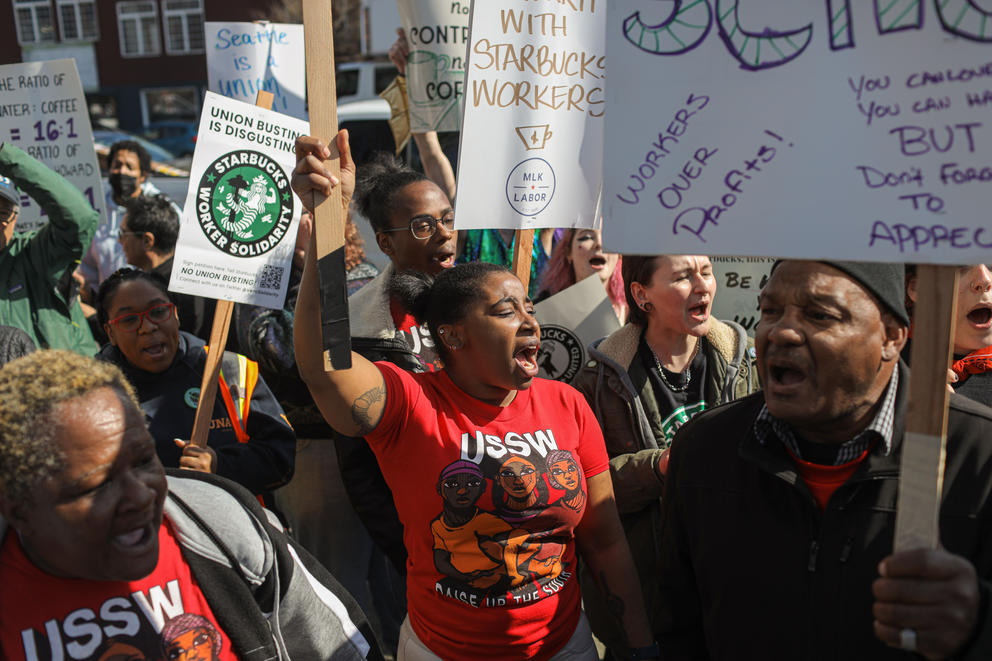a group of protesters chant and hold signs