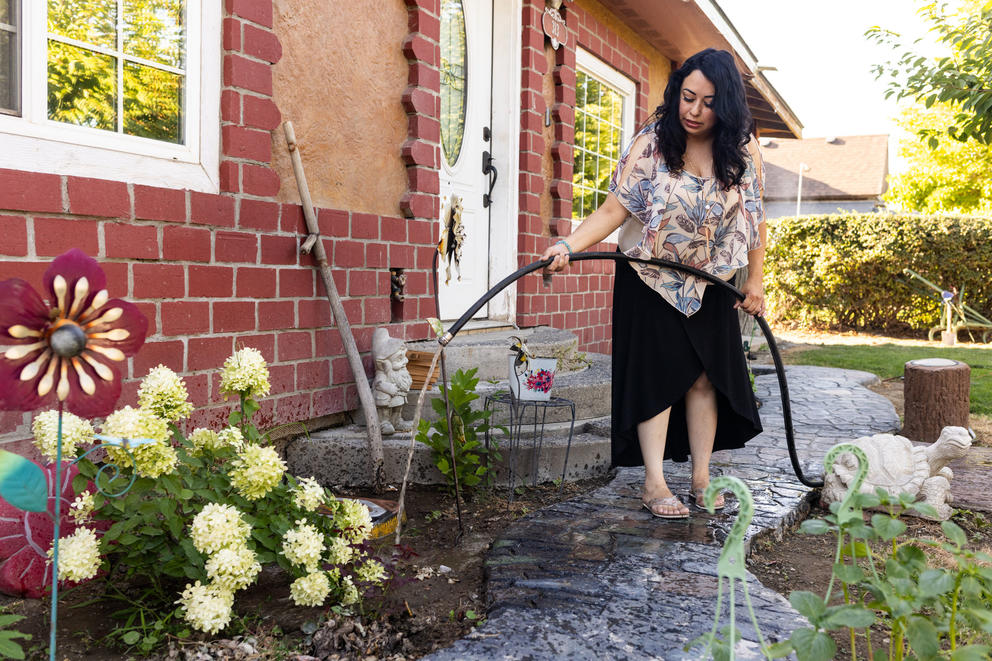 Silvia Zarate waters plants in the front yard of her home