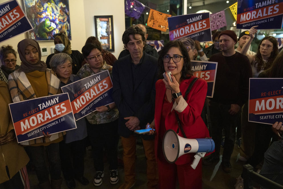 a woman speaks to a crowd on a megaphone