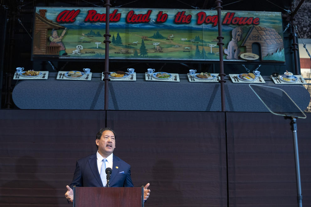 a man stands beneath a sign reading "all roads lead to the dog house" 