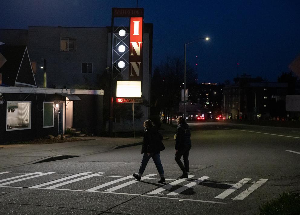 A pedestrian crosses the intersection of North 45th Street and Aurora Avenue North at night