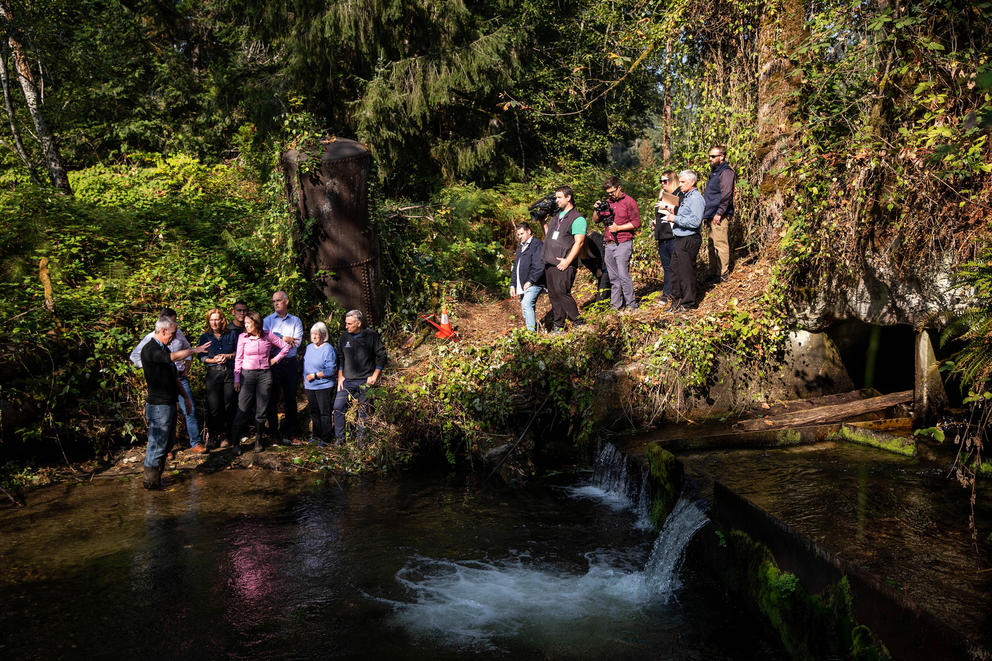 People stand next to a culvert.