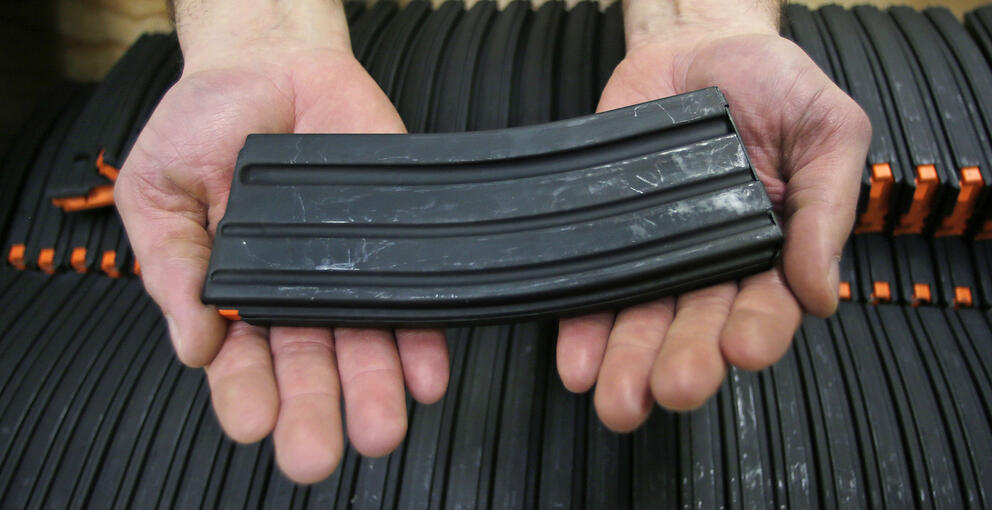 a pair of hands holding a high capacity magazine