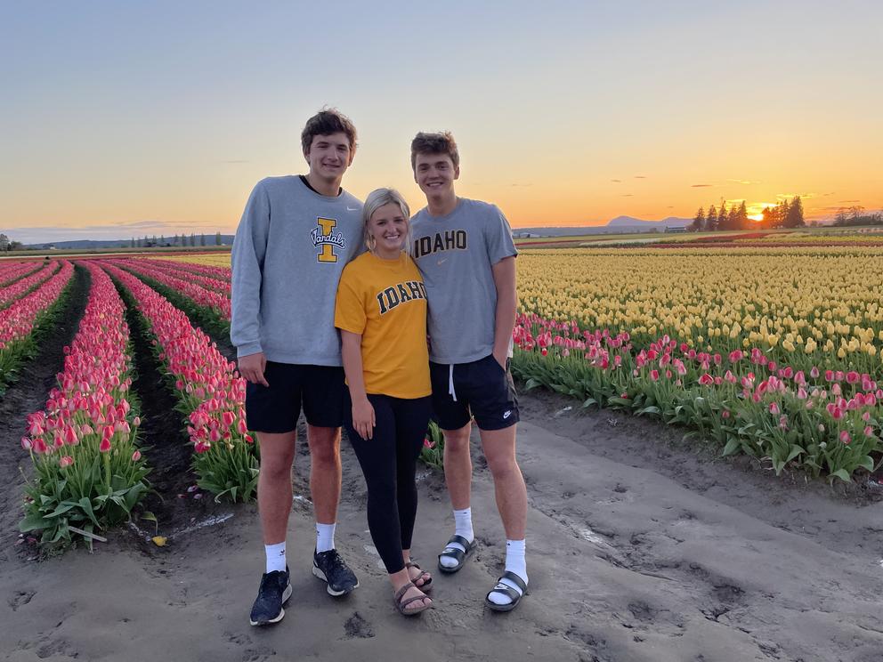 Three people stand in a tulip field.