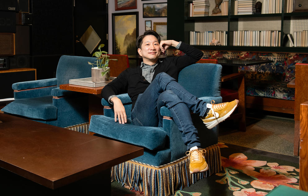 A person sits casually in an armchair posing for the camera