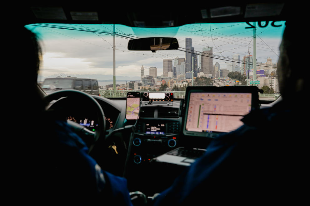 The Seattle skyline can be seen through the backseat of a police car. 