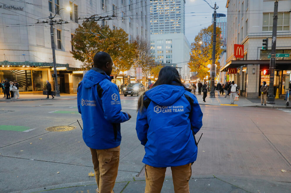 two people in blue jackets stand on the street in downtown seattle