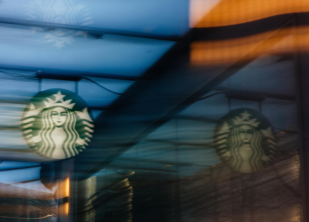 A green Starbucks signs streaks against a blue background in a slow-shutter image.