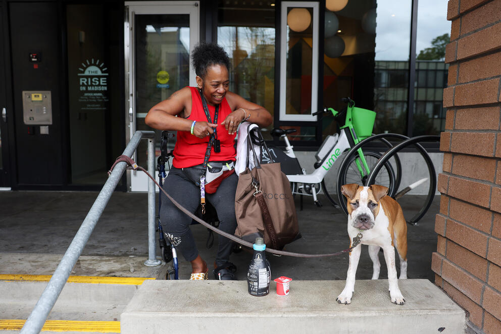 a woman sits outside on her walker with her brown and white dog on a leash next to her