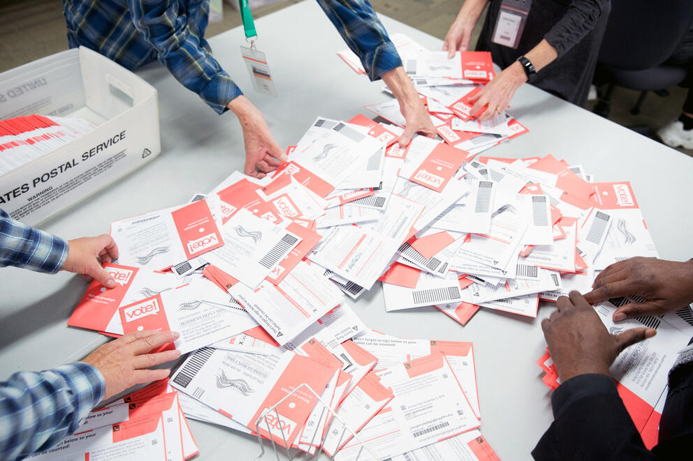 Hands sort through mail-in ballots