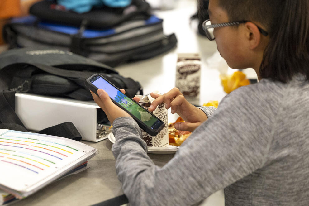 A student uses a smart phone during their lunch break at Goodman Middle School,