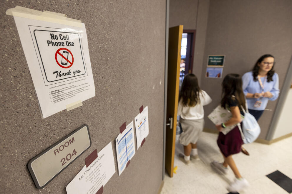 A sign that reads "no cell phone use" is pictured outside a classroom as students exit the room