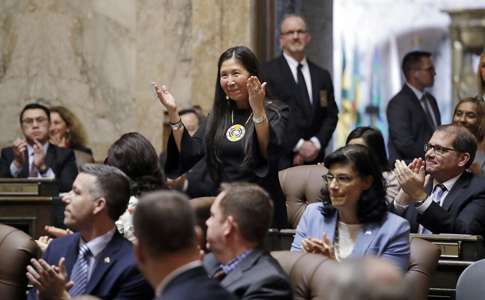 A person stands with hands palms up in an audience.